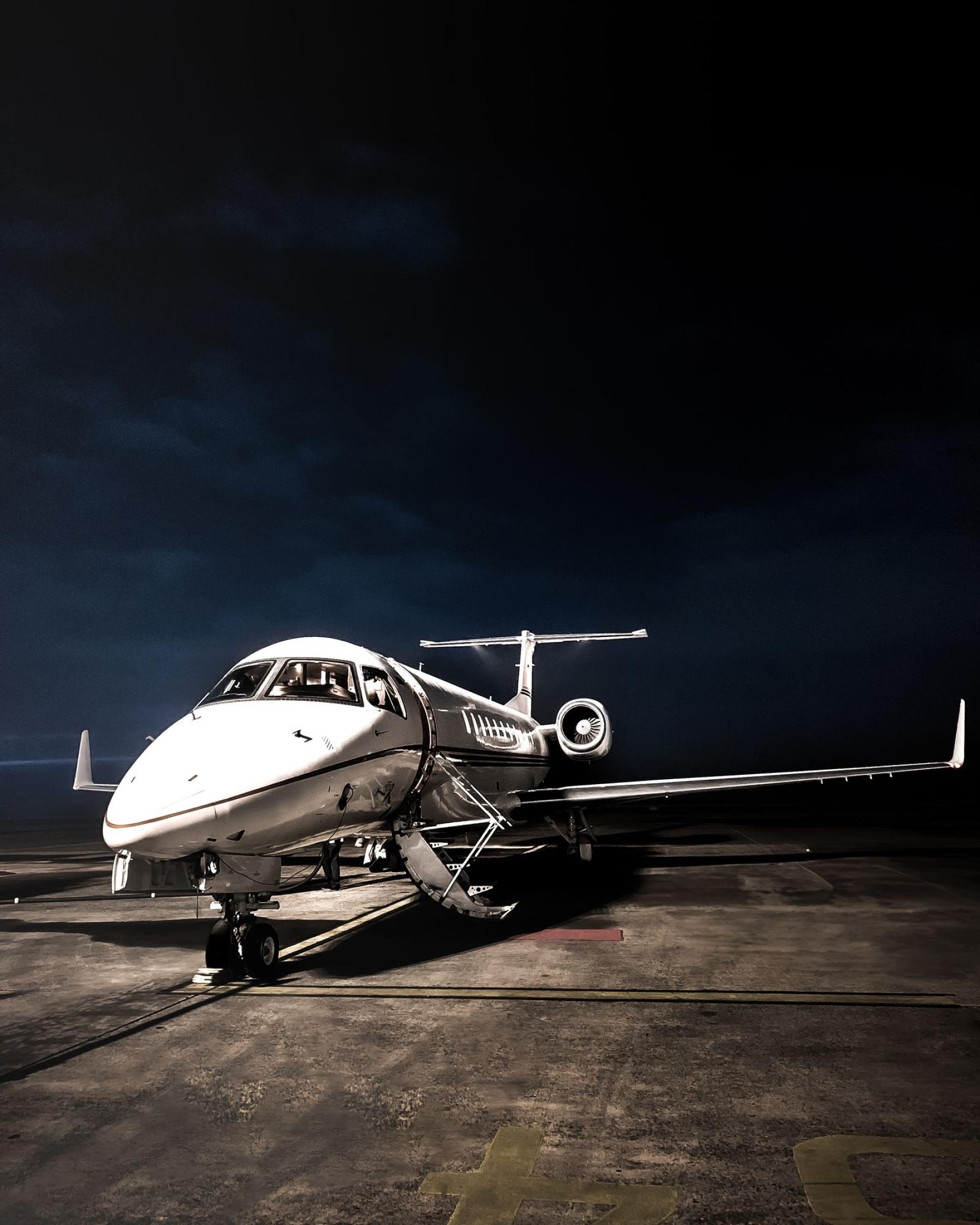 A private jet on a darkened apron, lit from one side